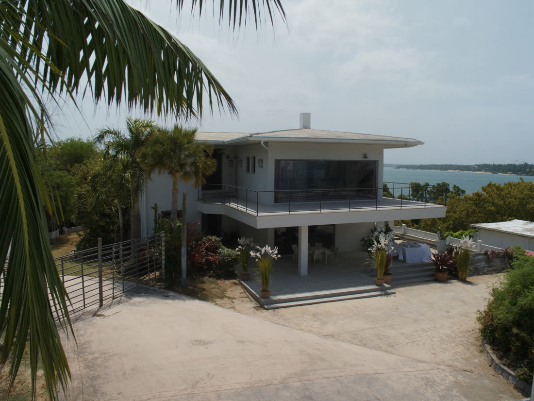 A bright coastal home with white siding near the water
